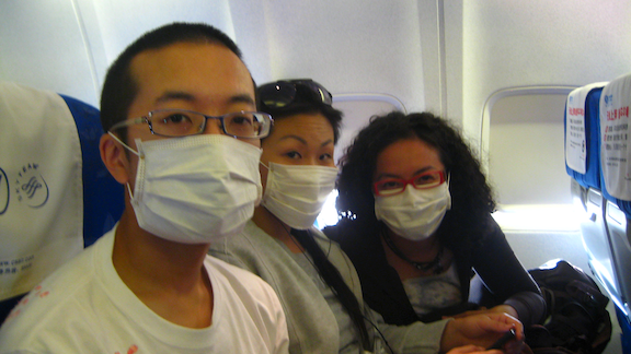 Three people wearing face masks on a plane