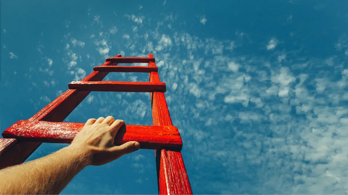 Wooden ladder pointing to the sky with a hand on it