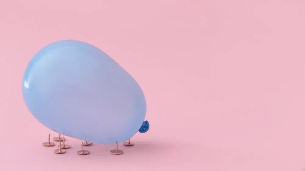 Blue balloon on nails in a light pink background