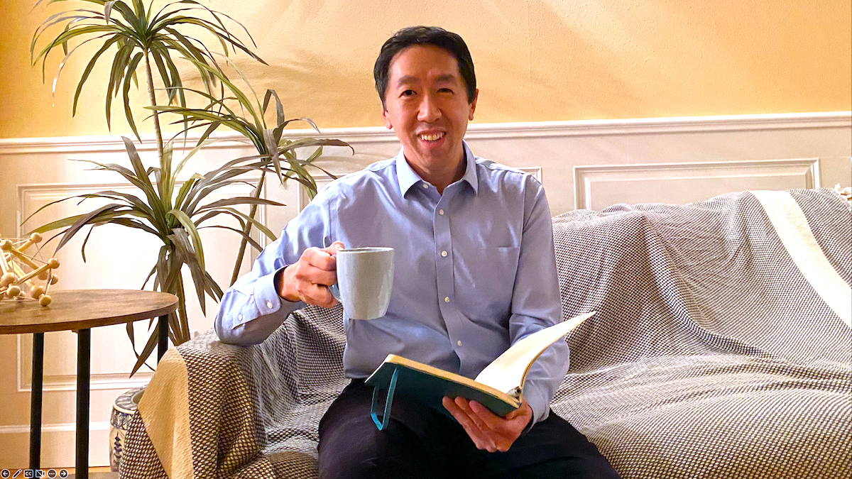 Andrew Ng on a couch with a cup of coffee and a book
